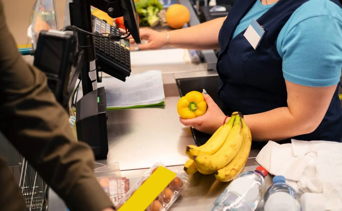 imagem mostra uma mulher trabalhando como caixa de supermercado.