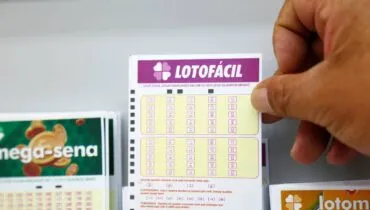 Imagem mostra um homem segurando canhoto de apostas da Lotofácil