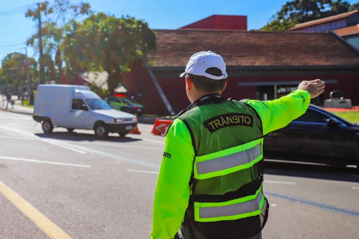 Agente de trânsito orienta motoristas em rua de Curitiba.