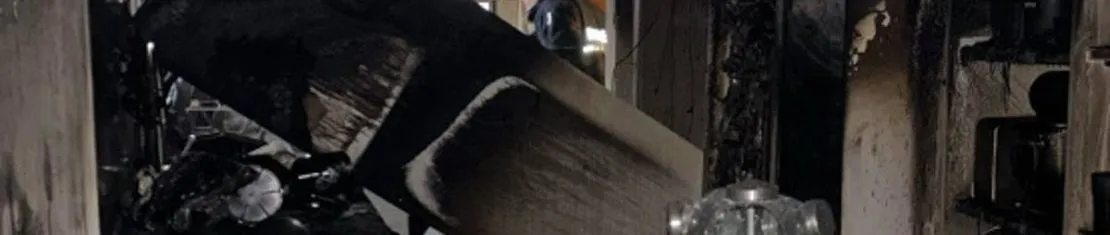 Imagem mostra o interior de um apartamento que pegou foto em Curitiba. Tem móveis queimados e tudo preto.