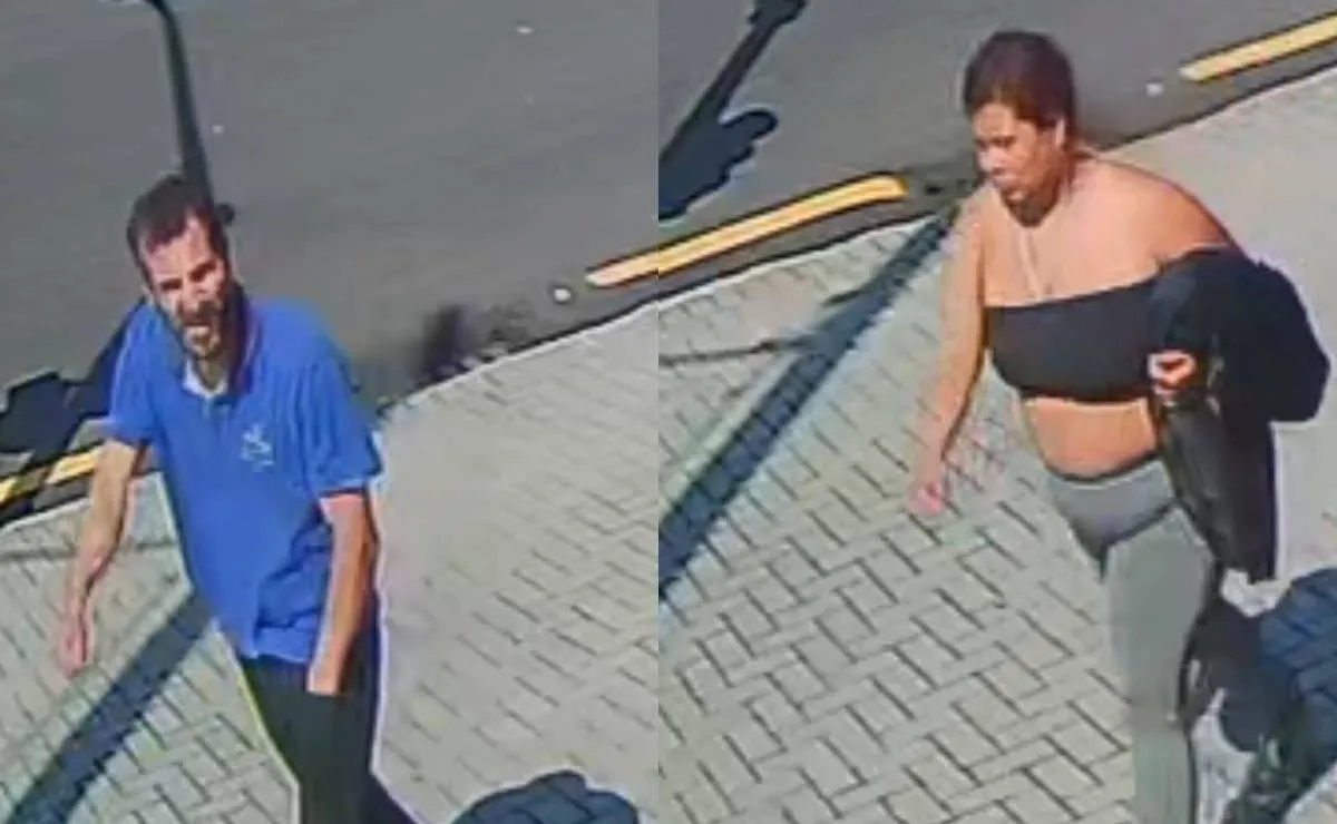 Imagem mostra um homem de camiseta azul e calça preta e uma mulher com top preto e calça cinza andando em uma calçada dom paver.