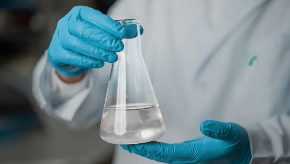 Na imagem, profissional com luvas segura um vidro com glicerina líquida.