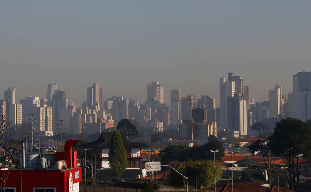Imagem mostra prédios de Curitiba com uma linha de poluição no horizonte.