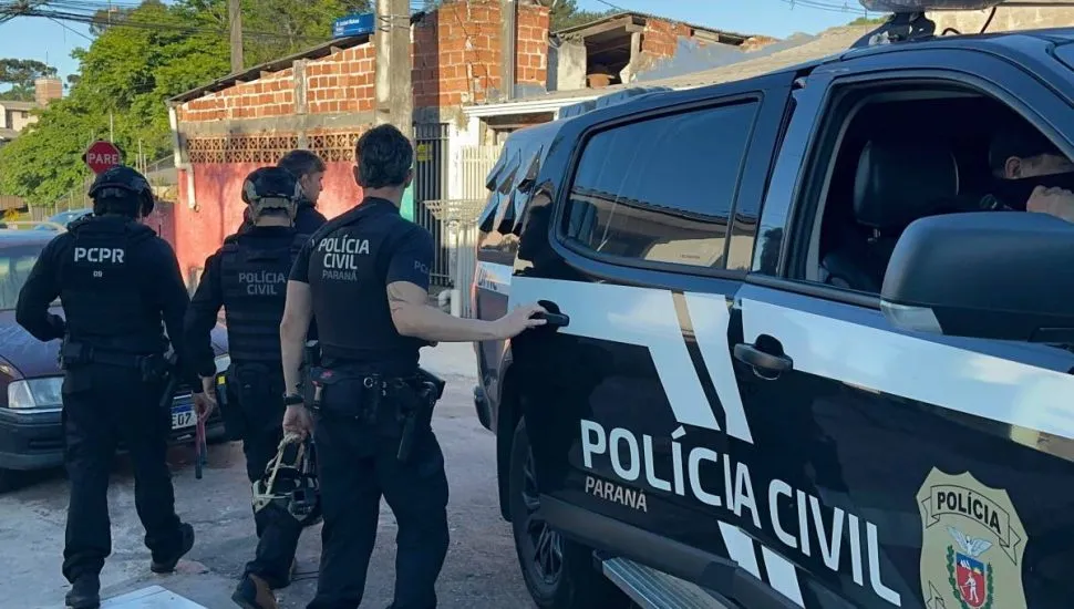 Imagem mostra uma viatura policial com policiais civis no entorno.
