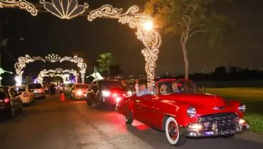 Imagem mostra um carro antigo desfilando no Natal de Curitiba.