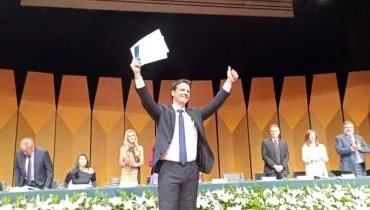 Imagem mostra o prefeito eleito de Curitiba Eduardo Pimentel com os braços erguidos em comemoração.