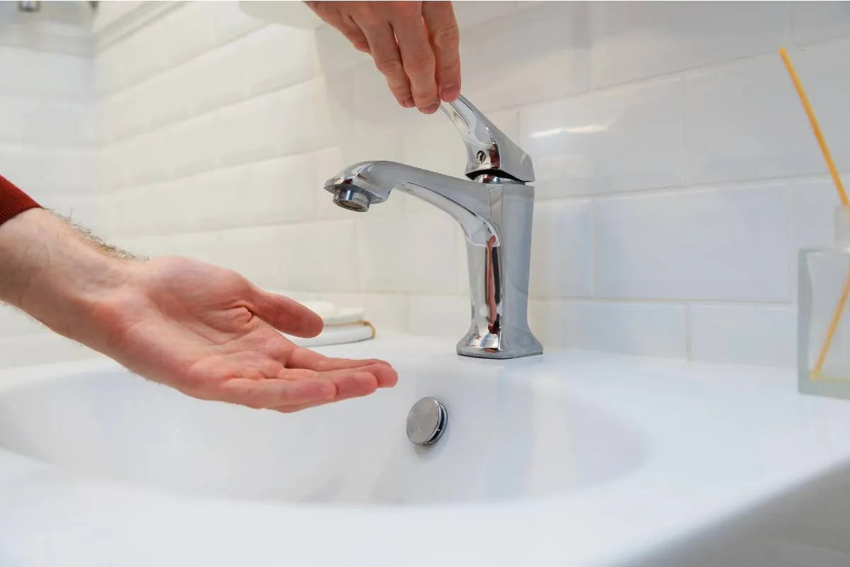 Imagem mostra uma pessoa tentando usar uma torneira sem água.