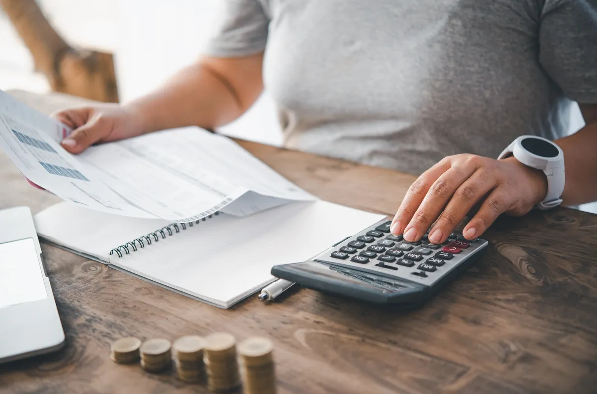 Imagem mostra pessoa fazendo cálculos e verificando contas