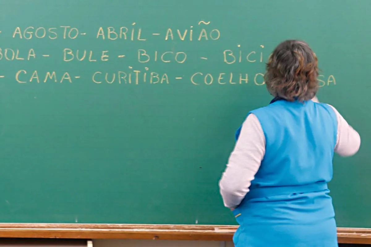 Imagem mostra uma professora escrevendo palavras em um quadro