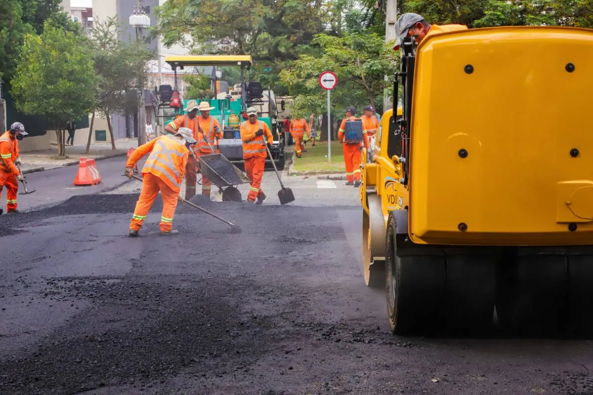 Imagem mostra uma equipe asfaltando uma rua.