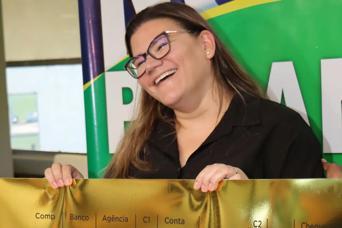 Na imagem, ganhadora de R$ 1 milhão segura o cheque simbólico do Nota Paraná.