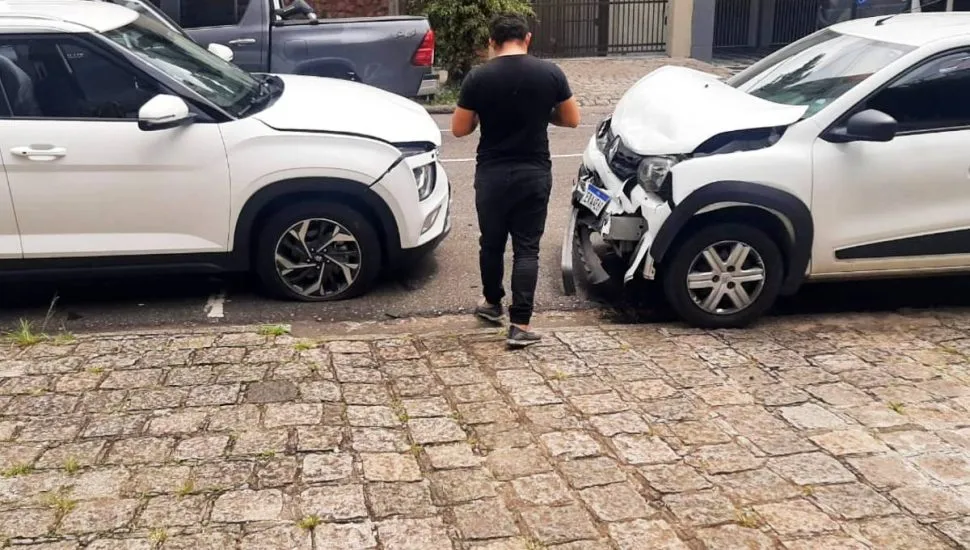 Imagem mostra dois carros brancos batidos de frente.