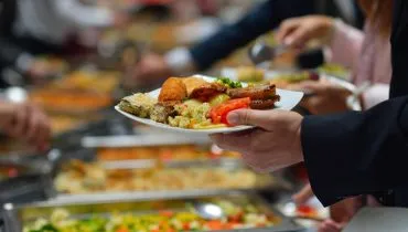 Imagem mostra pessoa pegando comida e colocando no prato