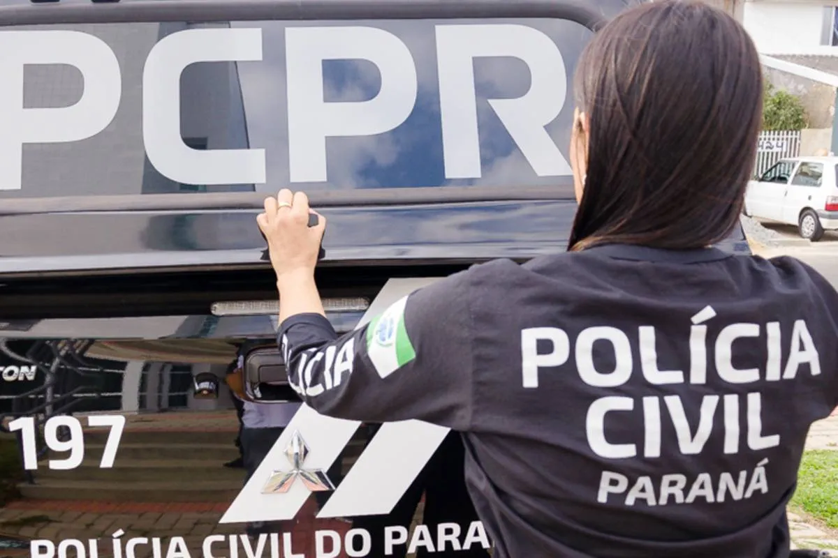 Imagem mostra uma policial fechando a caçamba de um camburão.