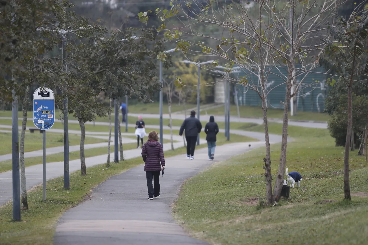 Imagem mostra pessoas caminhando no Parque Barigui, em Curitiba, em dia frio