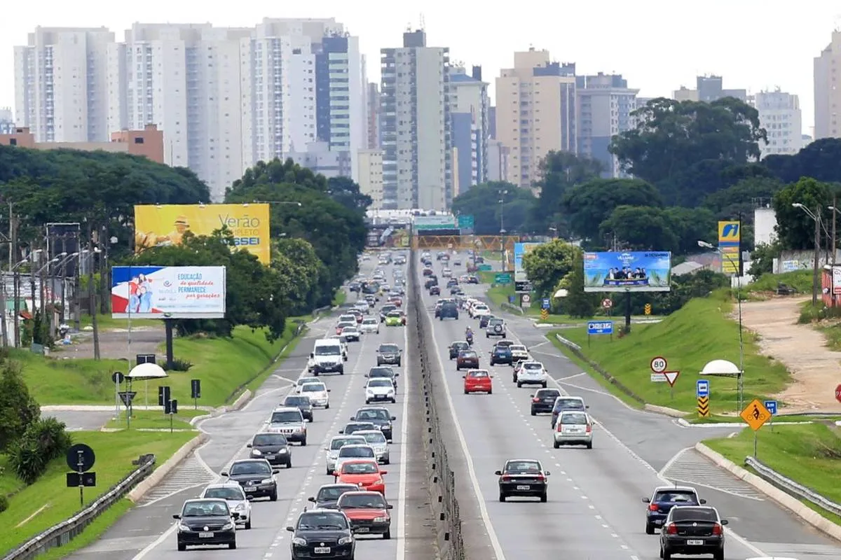 Imagem mostra o movimento na BR-277, em Curitiba. A saída está mais cheia que a chegada. Há prédios ao fundo e céu nublado.