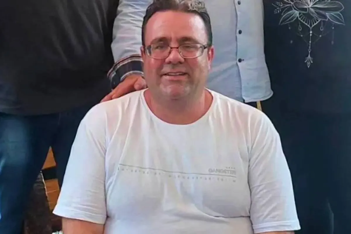 Imagem mostra o um homem sorrindo usando uma camiseta branca,