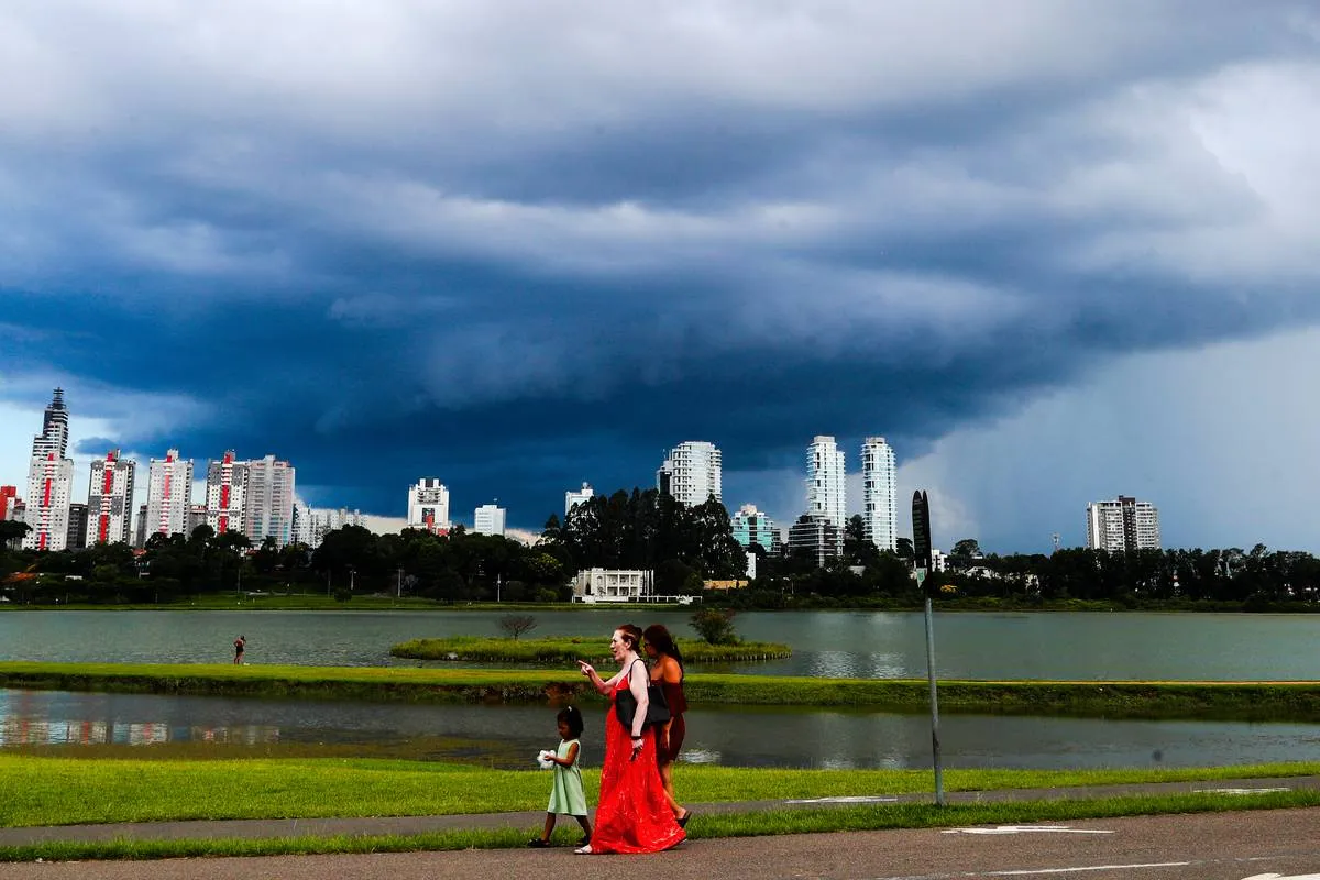 Imagem mostra uma nuvem gigante em Curitiba. Há um parque e pessoas caminhando.
