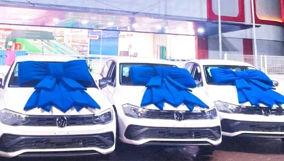 Imagem mostra três carros zero km com um laço azul no capo.