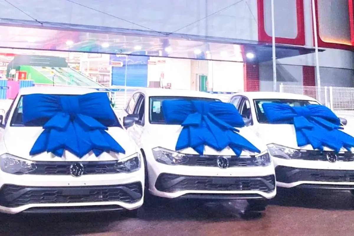 Imagem mostra três carros zero km com um laço azul no capo.