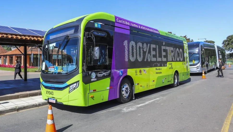 Imagem mostra um ônibus verde 100% elétrico.