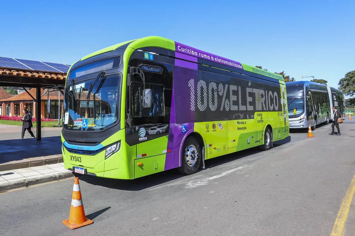 Imagem mostra um ônibus verde 100% elétrico.