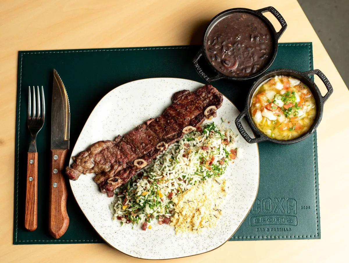 Assado de tira, acompanhando de arroz e farofa, uma cumbuca de feijão e outra de vinagrete