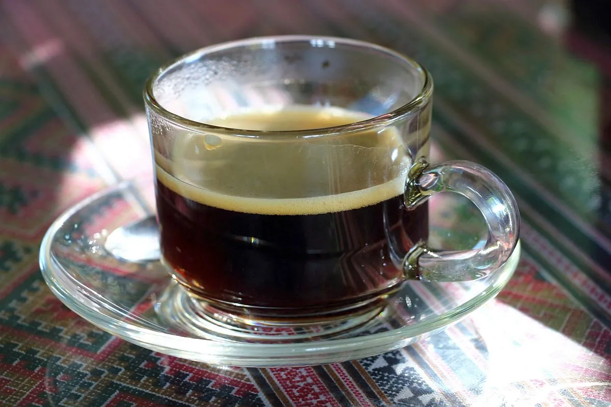 Timagem mostr auma xícara de café sobre um pires em cima de uma mesa