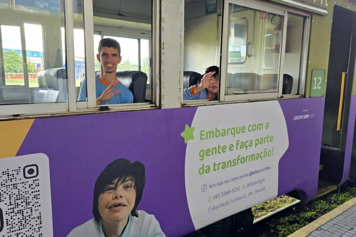 Imagem mostra pessoas dentro de um vagão de trem dando tchau para o fotógrafo..