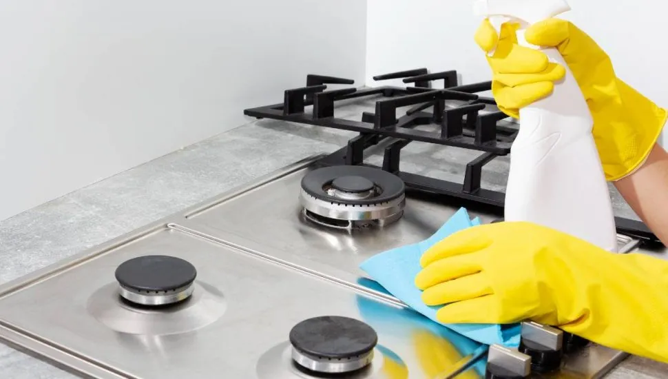 Imagem mostra uma pessoa limpando um fogão