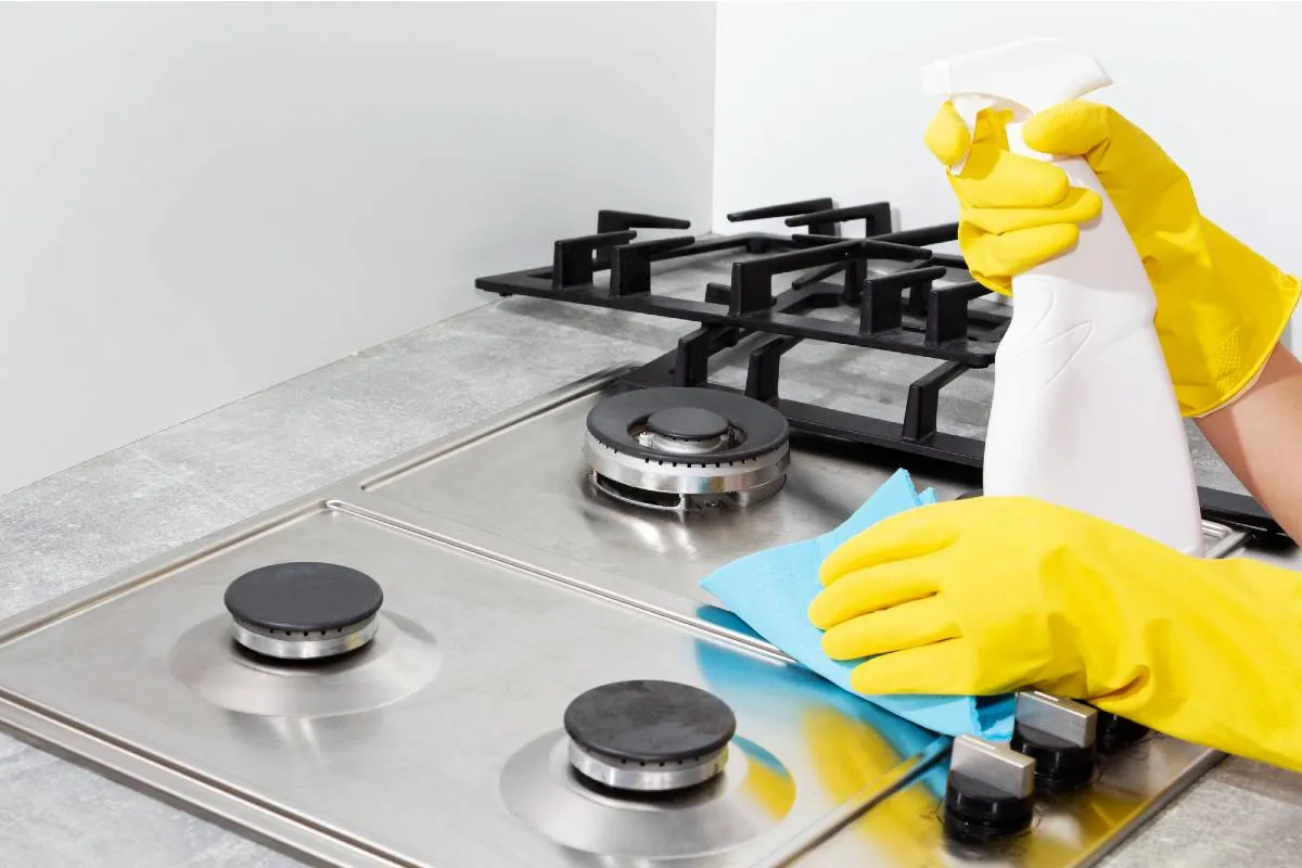 Imagem mostra uma pessoa limpando um fogão