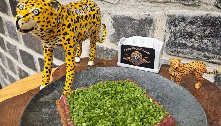 Imagem mostra uma carne de onça ao lado de duas miniaturas de onças