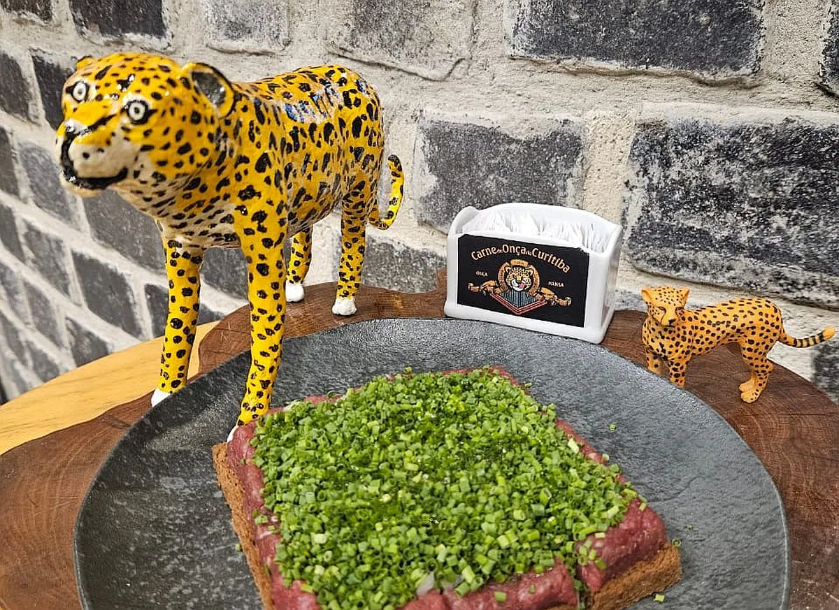 Imagem mostra uma carne de onça ao lado de duas miniaturas de onças