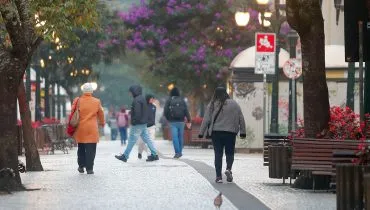 Imagem mostra o calçadão da Ruz Xv, em Curitiba, com várias pessoas caminhando agasalhadas