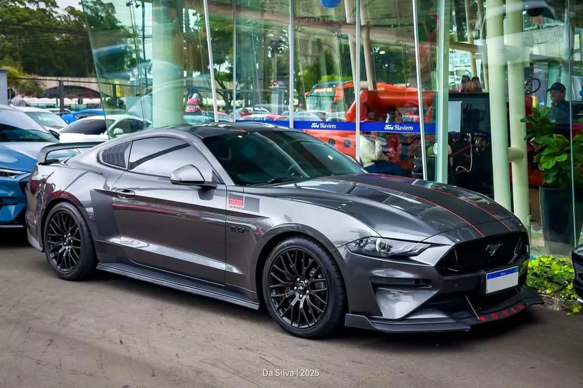 Imagem mostra um Ford Mustang cinza estacionado em uma loja