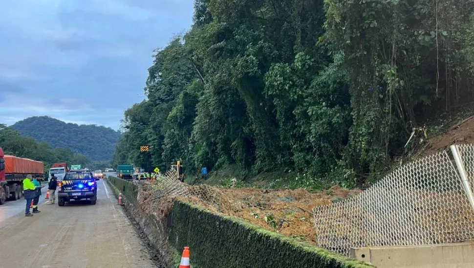 Imagem mostra a rodovia interditada por um deslizamento de terra e uma viatura da PRF.