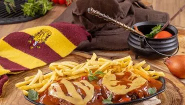 imagem mostra um prato de parmegiana, com fritas, e um cachecol e varinha de condão como objetos decorativos