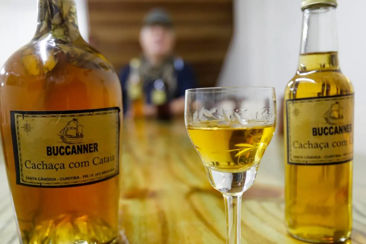 Imagem mostra uma garrafa e uma taça servida com cachaça de cataia.