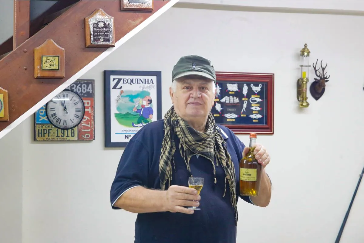 Imagem mostra um homem segurando uma taça e servindo cachaça.