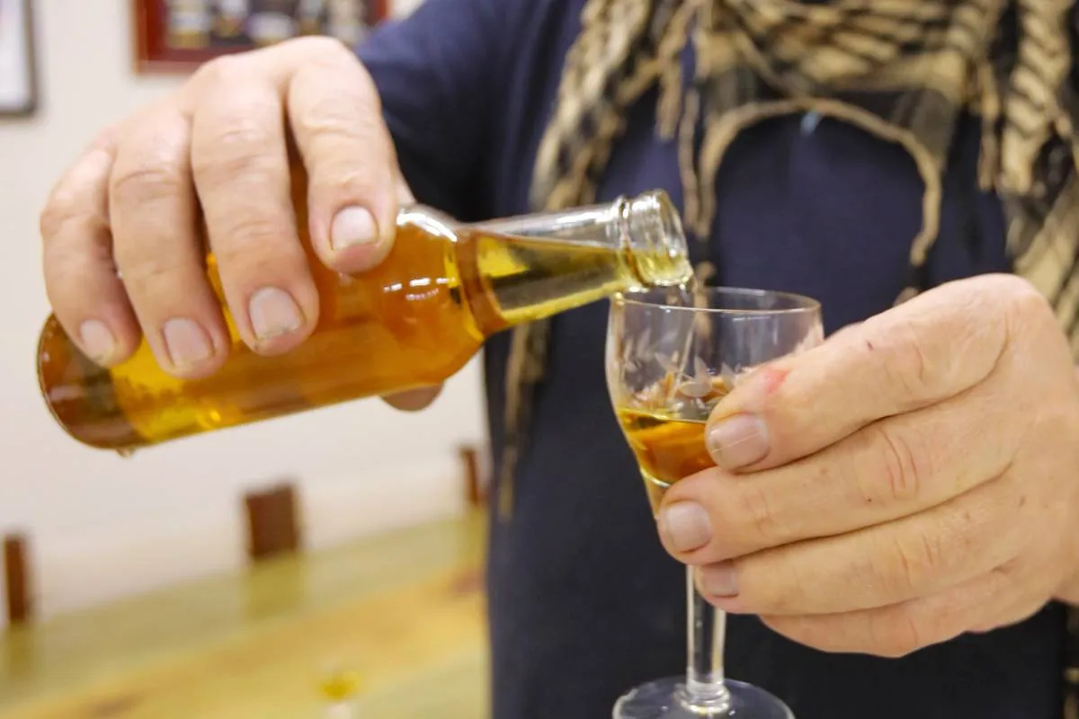 Imagem mostra uma garrafa e uma taça servida com cachaça de cataia.