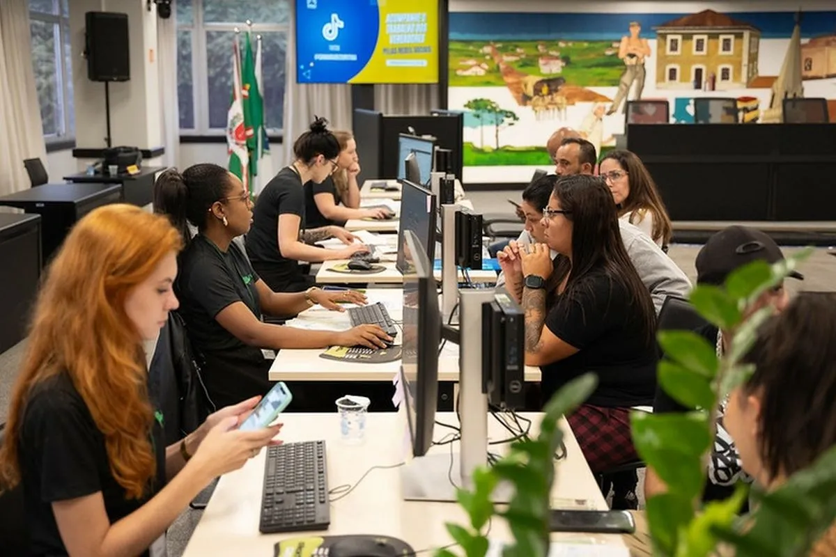 Na foto, dentro da Câmara, uma mesa grande com funcionários de um lado e a população de outro. Computadores no meio, entre eles