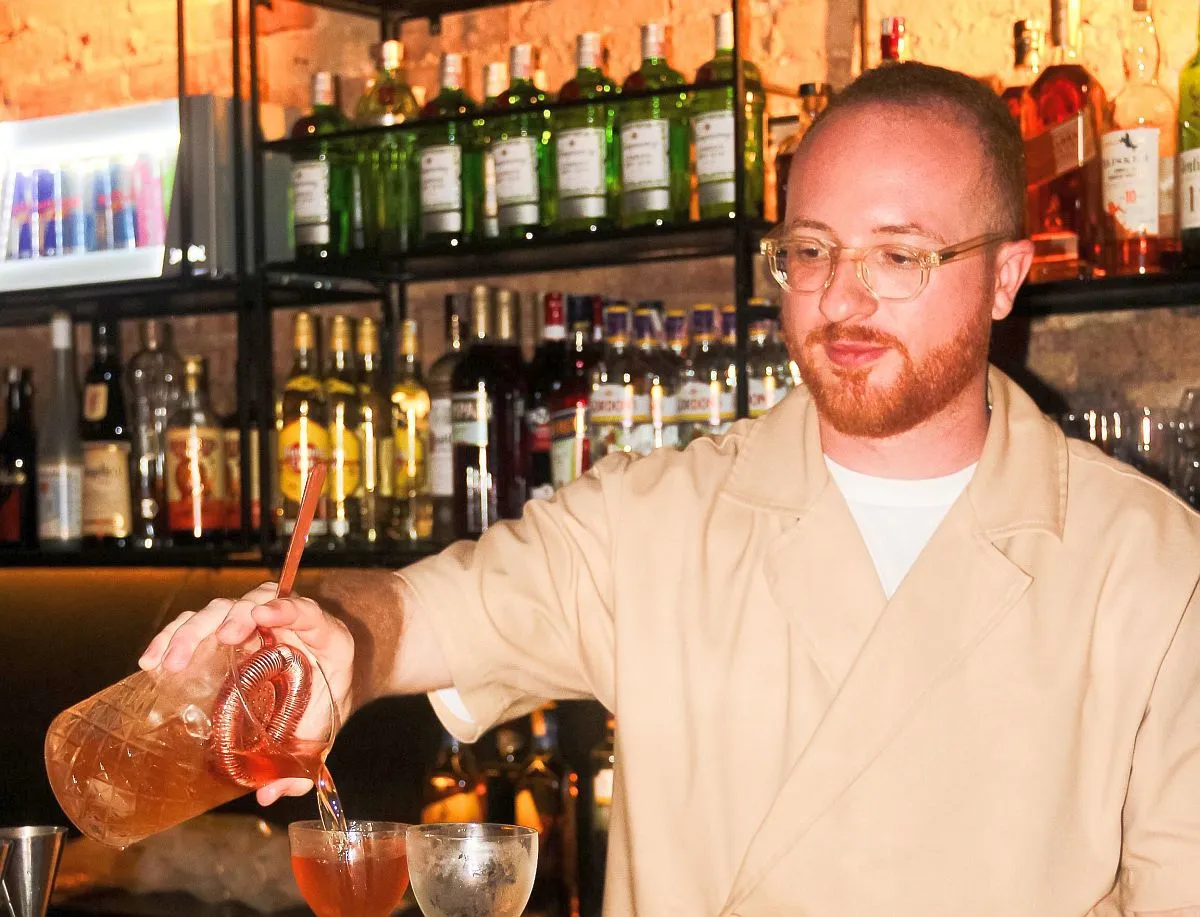 Imagme mostr ao bartender personagem da matéria fazendo uma bebida atras de um balcão de bar