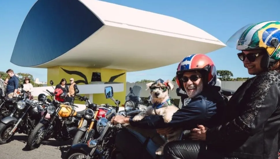 Imagem mostra Pancho em sua moto em frente ao Museu do Olho, em Curitiba.