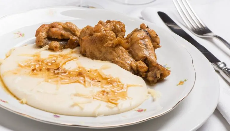 Imagem mostra um prato de frango com polenta.