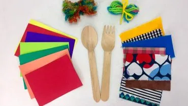 Imagem mostra vários objetos usados para produzir os bonecos e brinquedos da oficina, como talheres de madeira, pedaços de pano e lã