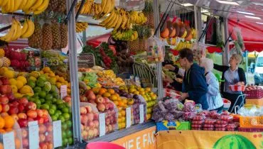 Imagem mostra clientes pegando frutas em uma banca repleta de opções