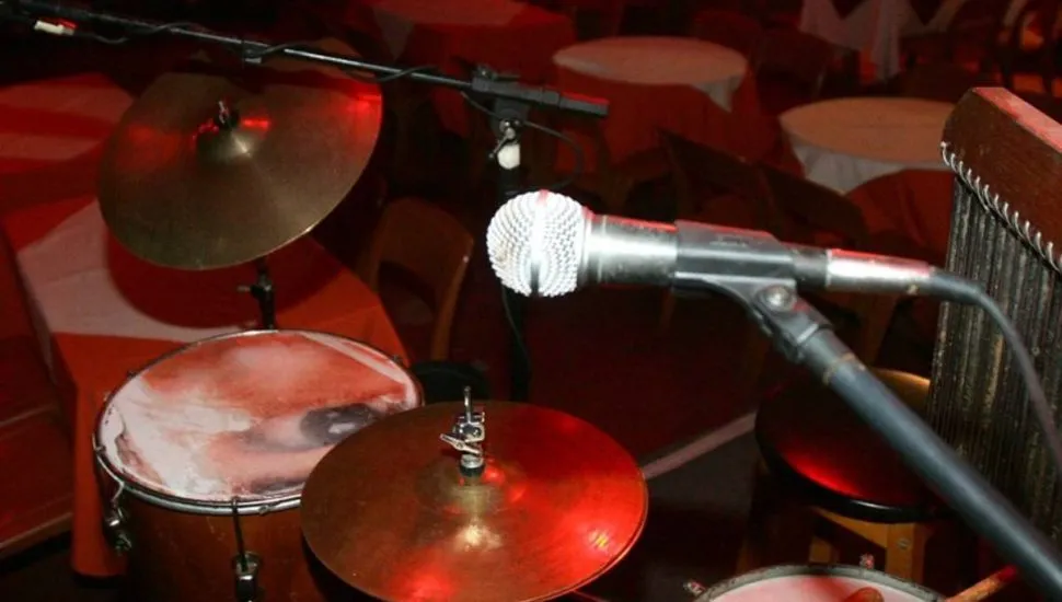 Imagem mostra uma bateria montada em um bar com detalhe no microfone.