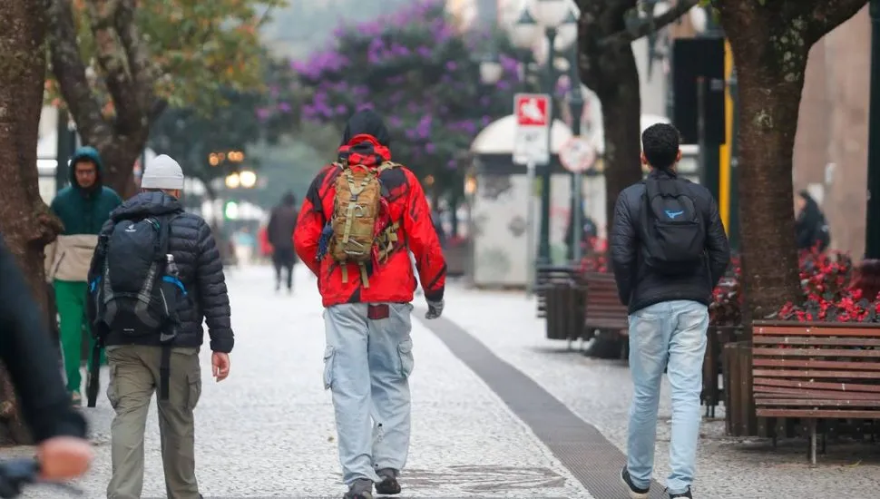 Imagem mostra pessoas com muito frio no Centro de Curitiba.