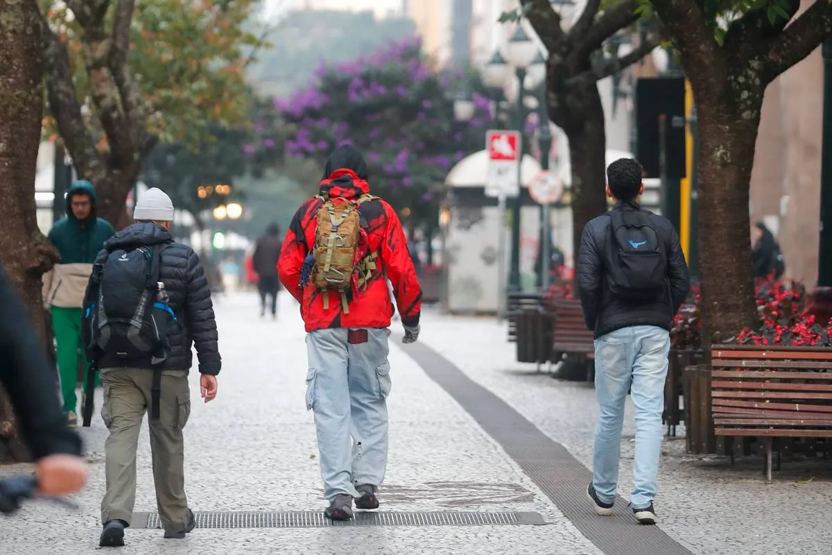 Imagem mostra pessoas com muito frio no Centro de Curitiba.