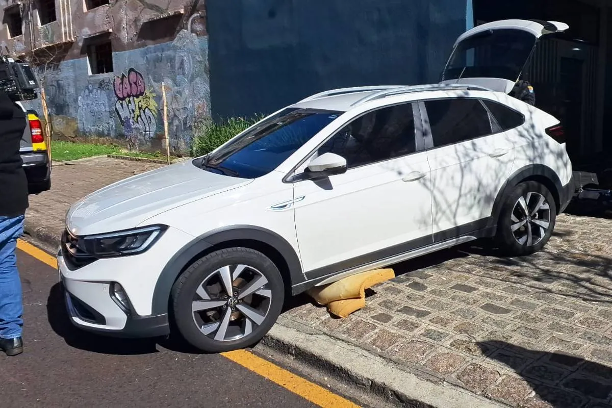 Imagem mostra um carro branco com pedaço de colhão em baixo.